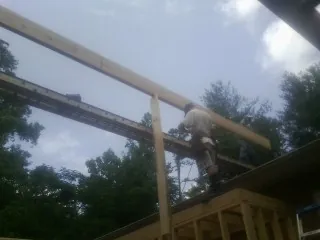 Carpenter setting a ridge beam over a new addition frame — Ice Dam Removal by Roofing Brothers in Landrum