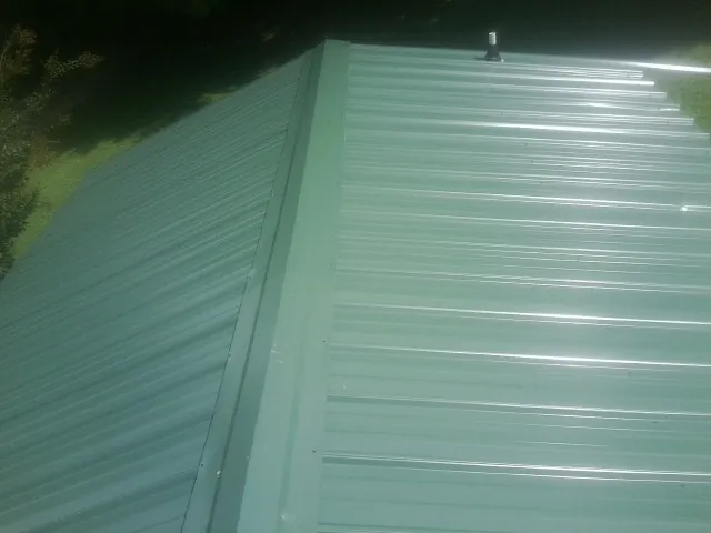 New green metal panels meeting at the ridge of a roof — Flat Roof Repair work by our crew in Landrum