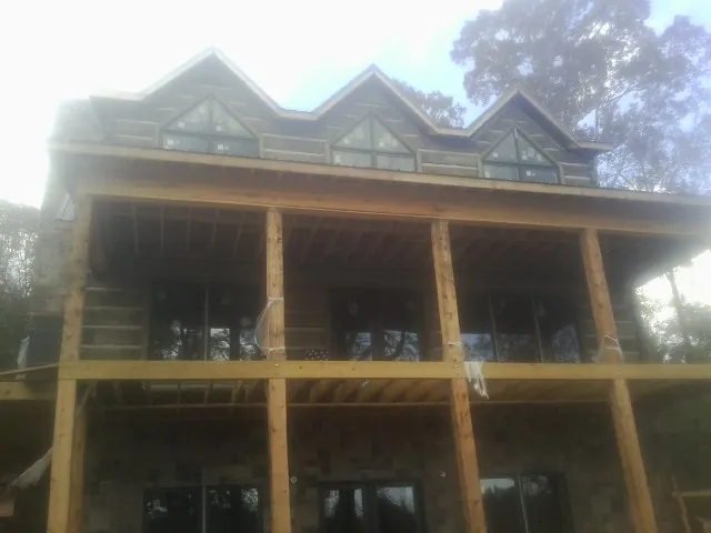 Dormers and porch framing on a large log home under construction — Roof Coating work by our crew in Landrum