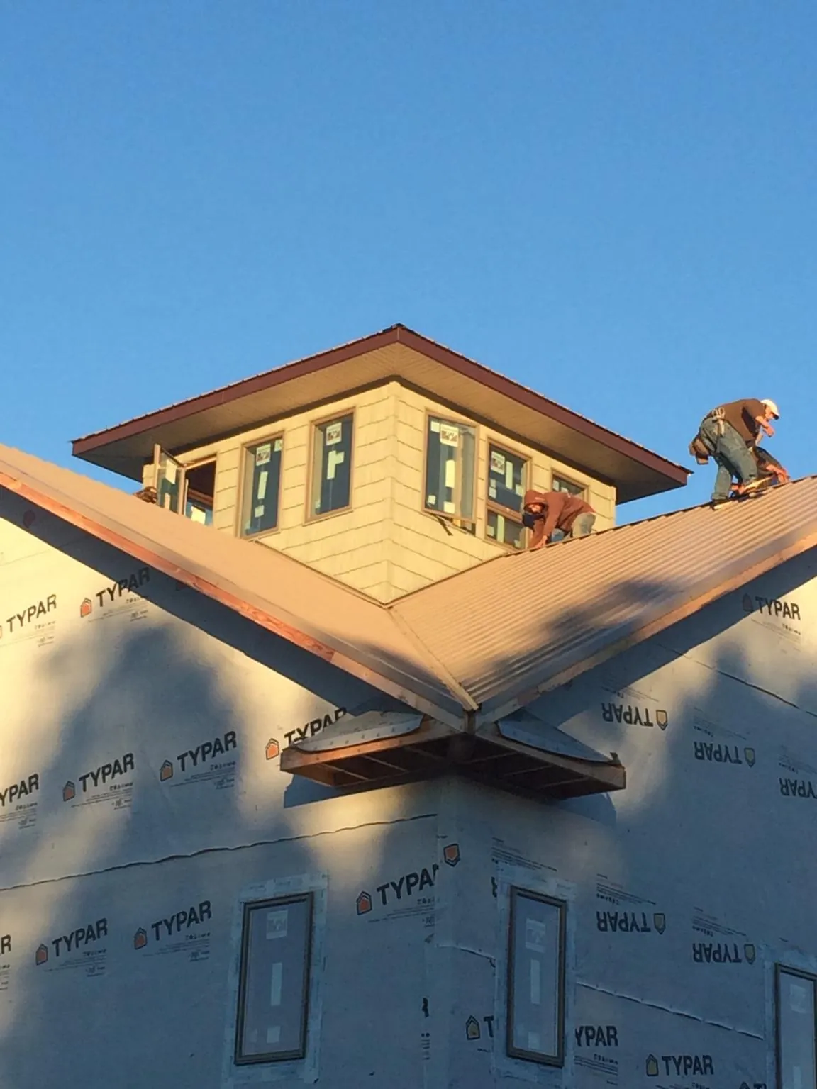 Roofers working around a rooftop cupola on a new metal roof at sunset — Roof Waterproofing in Landrum by Roofing Brothers